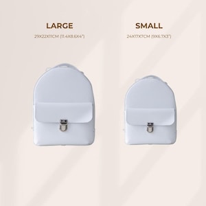 May include: Two white backpacks, one large and one small, are displayed. The large backpack measures 11.4 x 8.6 x 4 inches, while the small one is 9 x 6.7 x 3 inches. Each backpack has a flap closure with a silver-colored clasp.