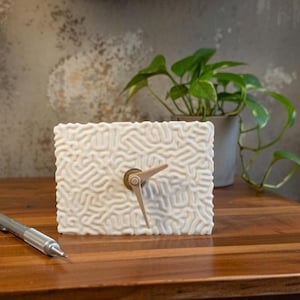 May include: A set of three ceramic mugs with a speckled, matte finish. The mugs are in shades of cream, light gray, and dark gray. Each mug has a simple, minimalist design and a rounded handle.