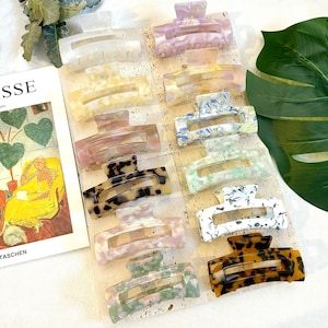 Puede incluir: Un juego de 12 pinzas para el pelo en varios colores y patrones. Las pinzas están hechas de plástico y tienen un diseño de caparazón de tortuga, mármol y floral.