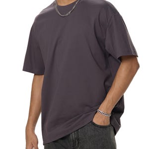 Puede incluir: Una camiseta gris antracita de gran tamaño con mangas cortas. La camiseta está hecha de una tela suave y cómoda y tiene un corte holgado.