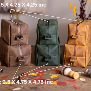 Peut inclure: Trois trousses de toilette en cuir de diff&eacute;rentes couleurs et tailles. Les trousses sont empil&eacute;es les unes sur les autres. Les trousses sont &eacute;tiquet&eacute;es avec les dates "2025", "3/21", "VIS", "ACR", "MC", et "V". Les trousses mesurent 8,5 pouces par 4,25 pouces par 4,25 pouces et 9,5 pouces par 4,75 pouces par 4,75 pouces.