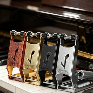 May include: Four piano pedal extenders in a row, each with a different finish: wood grain, gold, black, and silver. Each extender has a musical note cutout and a name engraved on it. The extenders are on a piano keyboard.