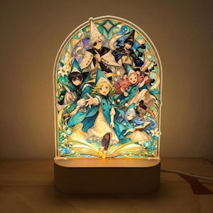 May include: A decorative LED lamp featuring a stained-glass style design with anime characters in teal robes and hats. The lamp has a wooden base and a warm, inviting glow, perfect for a bedroom or living room.