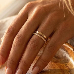 Peut inclure: Une tasse en céramique blanche avec une anse noire et le texte "But First, Coffee" dans un style manuscrit. La tasse est posée sur une surface blanche. La tasse mesure environ 10 cm de haut.