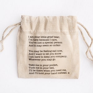 Puede incluir: Una peque&ntilde;a bolsa de tela beige con cierre de cord&oacute;n. La bolsa tiene un mensaje impreso que dice: "Soy tu peque&ntilde;o oso de la pena, Estoy aqu&iacute; porque me importa, Has perdido a una persona especial Y puede parecer tan injusto. Puede que te sientas triste ahora, Y quiero que sepas que Estoy aqu&iacute; para hacerte compa&ntilde;&iacute;a, Dondequiera que vayas. Ll&eacute;vame en tu bolsillo, M&eacute;teme en tu cama, Estar&eacute; ah&iacute; cuando me necesites, Y te tomar&eacute; la mano en su lugar. x"