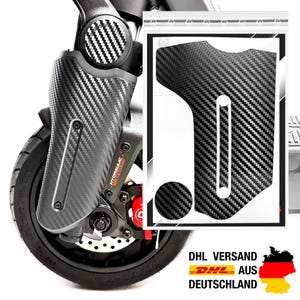 Könnte beinhalten: Ein Aufkleber-Set mit schwarzem Carbonfaser-Muster für die Vorderradgabel eines E-Scooters. Das Set enthält ein großes, geformtes Teil mit vertikalem Ausschnitt und ein kleines kreisförmiges Teil, abgebildet auf einer Gabel und in einer Tüte.