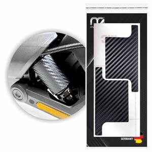 Könnte beinhalten: Ein Set aus zwei schwarzen Carbonfaser-Aufklebern für einen Drohnenarm, dargestellt in einer Verkaufsverpackung mit einem kreisförmigen Inset-Bild, das die Anwendung der strukturierten Folie auf dem grauen Kunststoffteil zeigt.