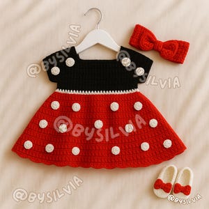 May include: A handmade crochet baby dress set in red, black, and white, resembling a cartoon character. The set includes a dress with white polka dots, a matching headband with a bow, and a pair of shoes with red bows.