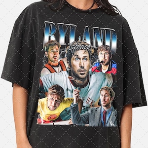 May include: Black t-shirt with a graphic design featuring the word "RYLAND" in a blue and silver font. The design includes multiple images of a person. The word "Grace" is also in the design.