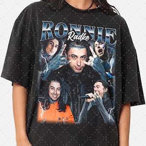 May include: Black t-shirt with a graphic print of Ronnie Radke, the lead singer of the band Falling in Reverse. The graphic features Ronnie Radke with other band members in a vintage style.