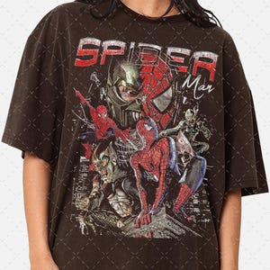 May include: A black t-shirt with a vintage-style graphic print of Spider-Man and other characters from the Spider-Man universe. The text "Spider Man" is printed in white on the shirt.