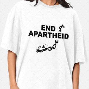 Könnte beinhalten: Ein weißes kurzärmeliges T-Shirt mit dem schwarzen Schriftzug END APARTHEID. Das Design enthält eine Grafik einer Strichmännchen-Figur, die sich aus einer Metallkette und einer Fessel befreit, platziert unter und rechts von der fetten Schrift.