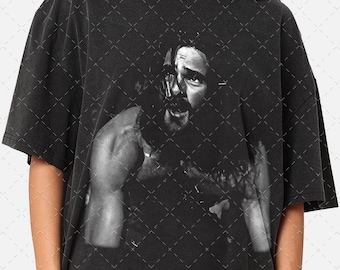 May include: Black oversized t-shirt featuring a black and white portrait of a person. The image is centered on the front of the shirt. The shirt has short sleeves and a crew neck.