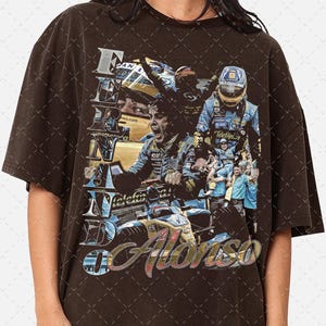 Puede incluir: Una camiseta marrón con un gráfico de estilo vintage de un piloto de carreras, Fernando Alonso, con un traje de carreras azul y amarillo. El gráfico incluye el texto "Fernando Alonso" y el número "66".
