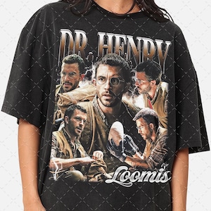May include: Black t-shirt featuring a collage of images of a man wearing glasses, with the text "DR. HENRY" in gold lettering at the top. The word "Loomis" is printed in white script at the bottom.