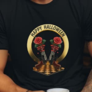 Op de afbeelding: Zwart T-shirt met een gouden en rode Halloween-afbeelding. De afbeelding bevat twee skeletgeweren met rode rozen en de woorden "HAPPY HALLOWEEN" in een gouden cirkel. De persoon houdt een witte mok vast.