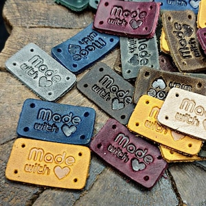 May include: Assortment of leather labels with the text "Made with" and a heart design in various colors, including brown, blue, red, and yellow.