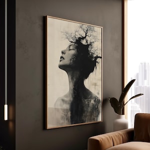 May include: Monochrome art print depicting a woman with tree-like branches as hair. The artwork is framed in a light brown wooden frame and hangs on a dark grey wall. The woman's eyes are closed, and her head is tilted upwards.