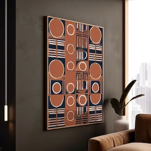 Può includere: Opera d'arte geometrica astratta da parete in una cornice di legno. L'opera presenta un motivo ripetuto di cerchi e quadrati color ruggine, strisce blu navy e bianche e forme geometriche. L'opera è esposta su una parete grigio scuro.