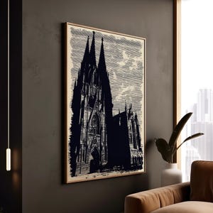 Puede incluir: Impresión en blanco y negro de una catedral enmarcada en madera. La obra de arte representa la fachada y las agujas de la catedral sobre un fondo claro. La impresión se muestra en una pared gris oscuro.