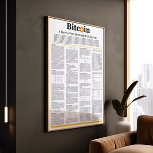 May include: A framed poster with the word "Bitcoin" at the top, featuring the text "A Peer-to-Peer Electronic Cash System." The poster has a white background with black text and yellow accents. It is hanging on a dark gray wall.