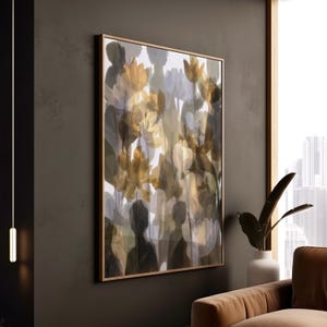 Könnte beinhalten: Abstrakter Blumendruck in einem goldenen Rahmen. Das Kunstwerk zeigt ein verschwommenes, geschichtetes Design mit Gold-, Grau- und Weißtönen. Das Gemälde wird an einer dunkelgrauen Wand mit einem Blick in ein modernes Interieur ausgestellt.