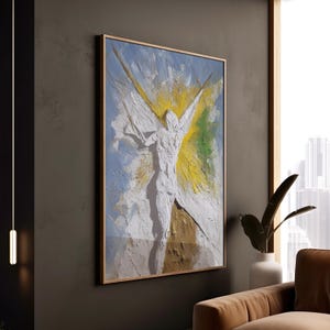 Pode incluir: Pintura abstrata emoldurada com um efeito texturizado tridimensional. A obra retrata uma figura branca com os braços estendidos sobre um fundo de pinceladas azuis, amarelas e verdes. A moldura é de cor castanho claro.