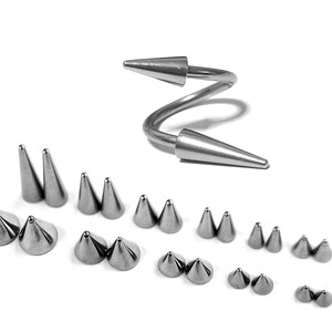 Puede incluir: Colección de joyería corporal plateada, que incluye una barra espiral y múltiples pares de tachuelas en forma de cono. La joyería se exhibe sobre un fondo blanco, mostrando la variedad de tamaños y estilos disponibles para piercings.
