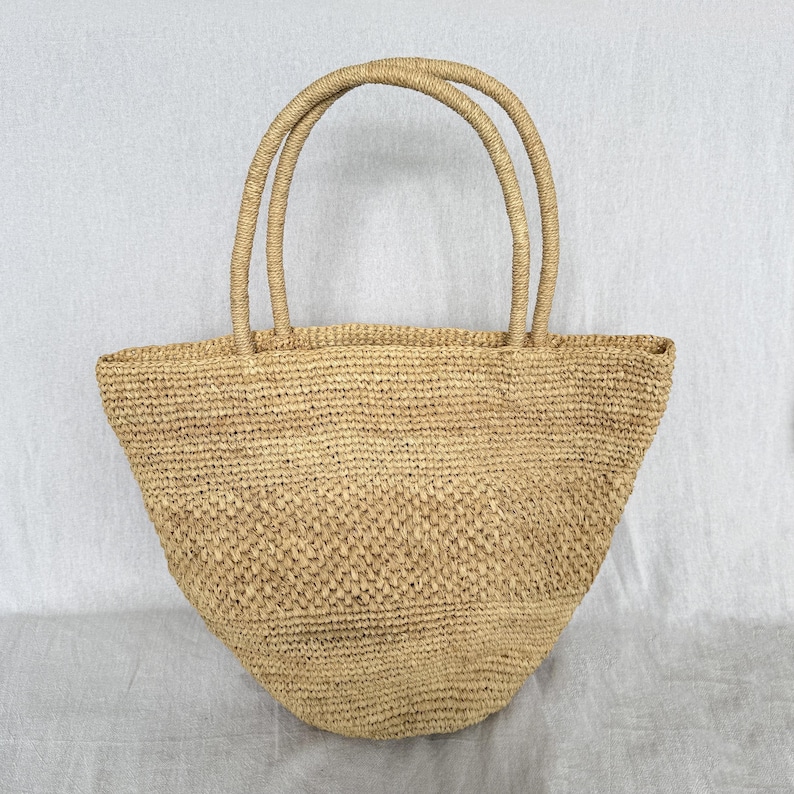 May include: A white ceramic mug with a black handle and the text "But First, Coffee" in a black, bold font. The mug is on a wooden surface. The mug is approximately 10 cm tall.