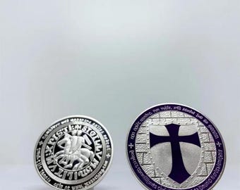 Könnte beinhalten: Zwei silberfarbene Ringe mit detaillierten Designs. Ein Ring zeigt einen Ritter zu Pferd und Text am Rand. Der andere Ring hat ein Kreuz auf einem Schild mit Text am Rand. Beide Ringe haben einen violetten Rand.