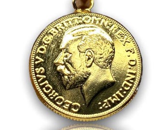 Könnte beinhalten: Ein goldener Anhänger mit einer Münze mit dem Profil eines Mannes und der Aufschrift "GEORGIVS V D.G. BRITT: OMN: REX F.D. IND: IMP:". Der Anhänger hat eine goldene Öse für eine Kette.