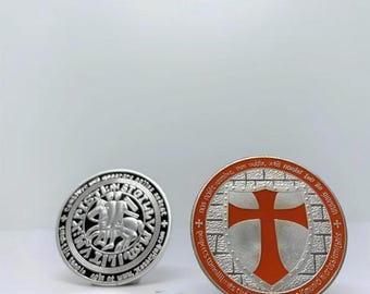 Könnte beinhalten: Zwei runde Münzen aus silberfarbenem Metall. Eine Münze zeigt einen Ritter zu Pferd, die andere ein rotes Kreuz auf einem Schild. Beide Münzen haben Text am Rand. Sie liegen auf weißem Hintergrund.