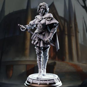 May include: A grey, unpainted miniature figurine of a warrior standing on a circular, ornate base. The figure wears a structured jacket, a short skirt, and tall boots, holding a sword in one hand and wearing a cape draped over the shoulders.