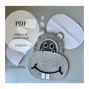 May include: A gray, rope-style hippo-shaped craft project. The hippo has black eyes, a black smile, and white teeth. The image includes paper templates and the text "PDF TEMPLATE DOWNLOAD ENGLISH + TUTORIAL".