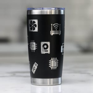 May include: A black stainless steel tumbler with a silver lid. The tumbler is decorated with a pattern of computer hardware icons, including a hard drive, a circuit board, a USB drive, a router, and a fan.