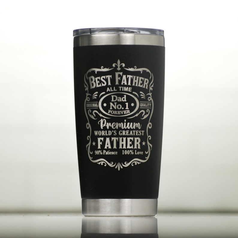 Op de afbeelding: Een zwarte ge&iuml;soleerde beker met een zilveren rand en deksel. De beker heeft de tekst "BEST FATHER ALL TIME Dad No. 1 FOREVER Premium WORLD'S GREATEST FATHER 90% Patience 100% Love" in een decoratief lettertype.