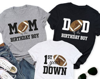 May include: Three gray, black, and white t-shirts with the text "Mom of the Birthday Boy", "Dad of the Birthday Boy", and "1st year down" with a football graphic.