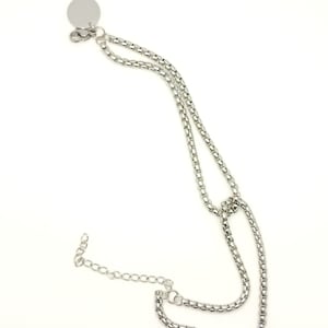 May include: A silver chain necklace with a round pendant. The chain is made of small, linked squares.