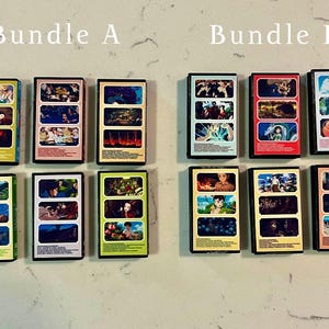 May include: Two bundles of collectible VHS tapes, labelled "Bundle A" and "Bundle B". Each tape features colourful artwork from animated films. The tapes are rectangular with black borders and are arranged on a light-coloured surface.