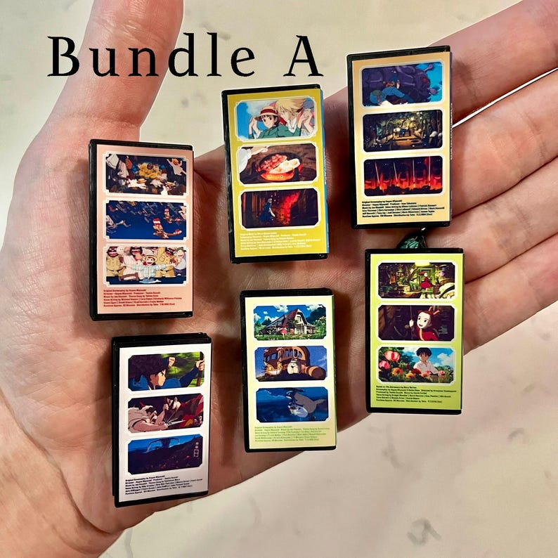 May include: A selection of small, rectangular artworks displaying vibrant anime scenes. The text "Bundle A" is visible. Each piece has a black border and depicts various animated characters and settings.