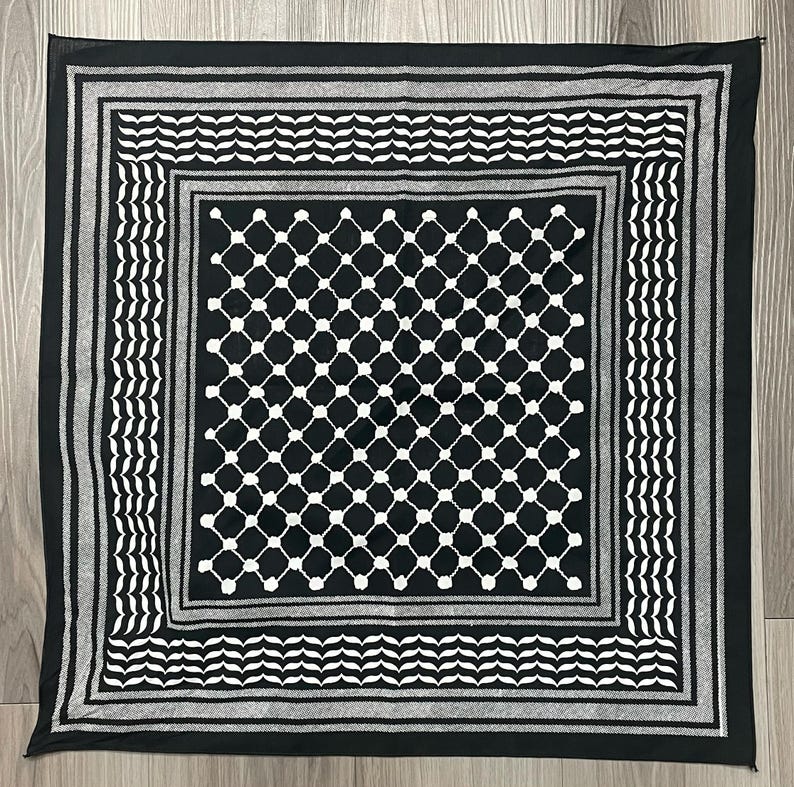 May include: Square black and white scarf with a geometric pattern. The scarf features a central diamond grid design, framed by borders of alternating stripes and wave-like patterns. The scarf is made of a soft material and is suitable for various uses.