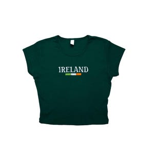 May include: A dark green cropped t-shirt with short sleeves and the word "IRELAND" in white lettering with the Irish flag underneath.
