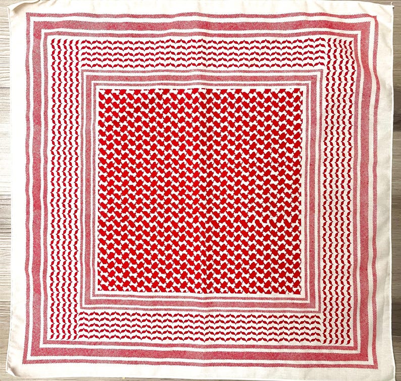May include: A square, off-white scarf with a red and white pattern. The scarf features a central field of red and white geometric shapes, framed by a red border and a white edge with red stripes. The design is symmetrical.