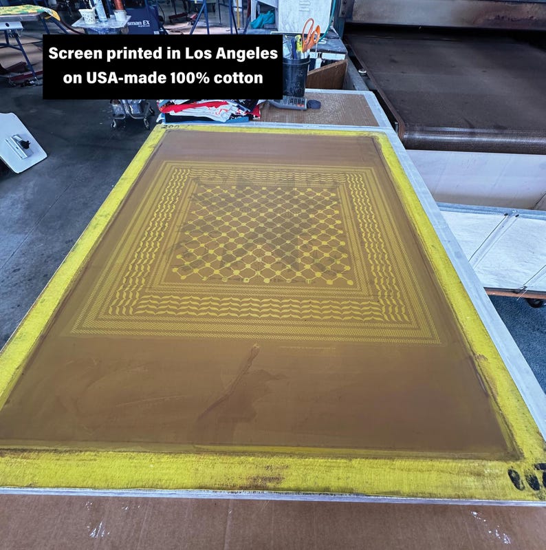 May include: A screen printing frame with a yellow border and a brown screen. The screen features a geometric pattern in yellow. Text on the image reads "Screen printed in Los Angeles on USA-made 100% cotton."