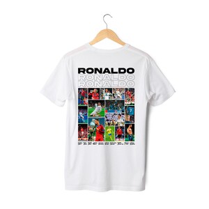 Może przedstawiać: Biała koszulka z kolażem zdjęć Cristiano Ronaldo na plecach. Zdjęcia są ułożone w siatkę i obejmują obrazy Ronaldo grającego w piłkę nożną, świętującego gole i trzymającego trofea. Tekst "RONALDO" jest powtórzony trzy razy pogrubioną czcionką bezszeryfową.