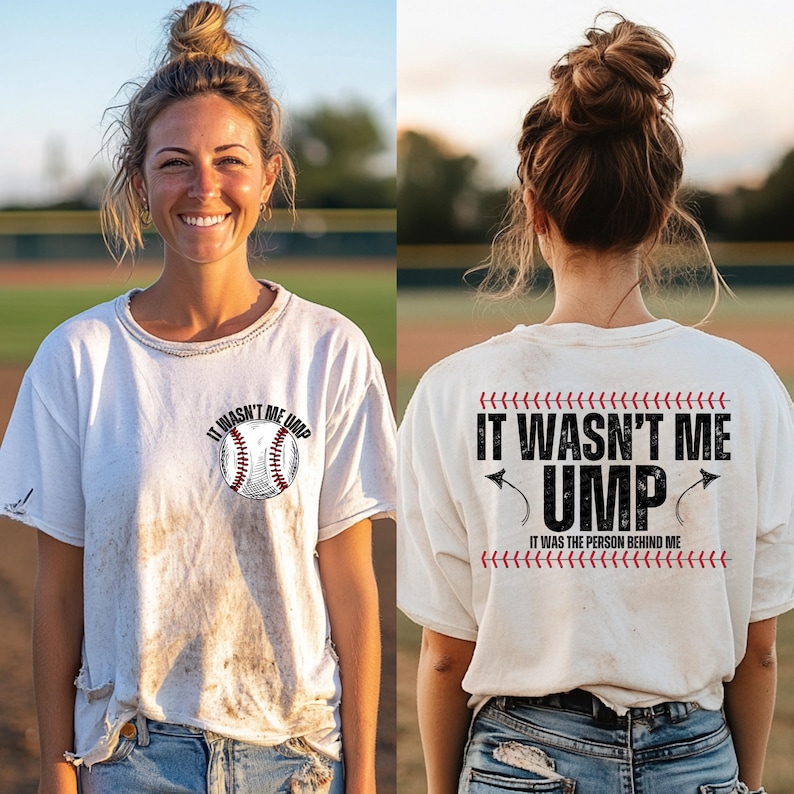 May include: White t-shirt with a baseball graphic and the text "It wasn't me ump" on the front. The back of the shirt has the text "It wasn't me ump it was the person behind me" with a baseball stitch design.
