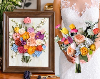 May include: A framed three-dimensional floral artwork featuring a colorful bouquet of paper flowers in shades of orange, pink, yellow, purple, and blue, set against a textured white background within a dark brown wooden frame, alongside a matching bouquet.