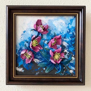 May include: A framed painting of pink flowers with green leaves on a blue and black abstract background.