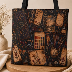 May include: A black tote bag featuring a repeating pattern of art supplies including a sketchbook, watercolor palette, paintbrushes, ink bottles, and paper tags with the text "CREATE BEAUTY EVERY DAY" and "ART IS THE HIGHEST FORM OF HOPE."
