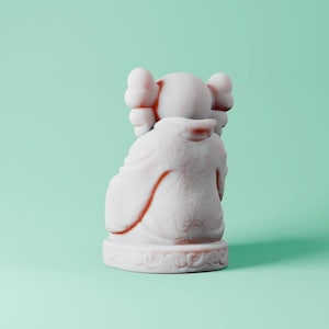 May include: White ceramic figurine of a cartoon character with large ears and a rounded body. The figurine is sitting on a base with a decorative design.